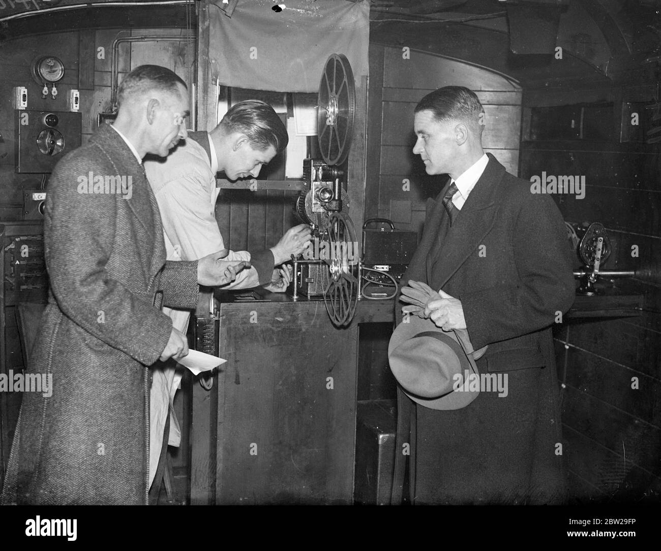Il regista tedesco vede il cinetreno britannico. Herr Muller Hillebrand, responsabile del dipartimento cinematografico tedesco delle ferrovie, invitato a mostrare alcuni film ai funzionari delle ferrovie britanniche, ha visitato King's Cross Station, Londra, e ha ispezionato lo speciale allenatore cinematografico. Questo pullman è dotato di un cinema in miniatura. Spettacoli fotografici, Herr Muller Hillebrand (a destra), che ispezionano il proiettore in pullman presso la stazione di King's Cross. 27 novembre 1937 Foto Stock