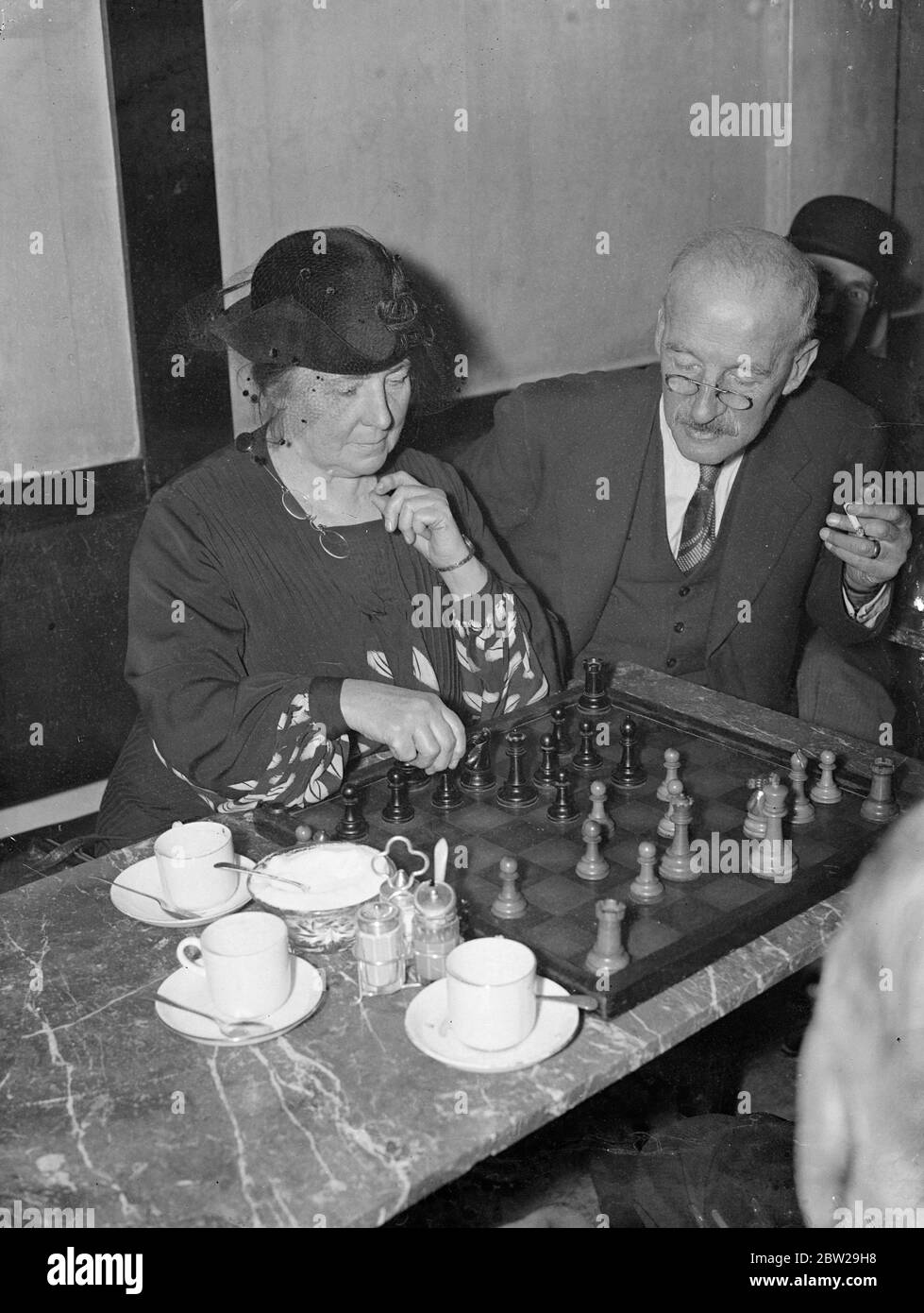 Il campione delle donne gestisce il caffè della città dedicato a scacchi. Seduti in un silenzio rotto solo dalle tazze da caffè, gli scacchi 'amici' hanno trovato un rifugio in un caffè della City of London, chiamato in modo appropriato 'The Gambit' in Budge Row. L'unico caffè al mondo interamente dedicato agli scacchi, è gestito dalla signorina Edith Price, che è stata a Buge Row per 37 anni e che è stata quattro volte campione di scacchi della Gran Bretagna. Molti dei giocatori provengono da tutte le parti di Londra e alcuni rimangono fino a mezzanotte. Foto mostra, Miss Edith Price pensando a una mossa durante un gioco con uno dei suoi clienti al 'GA Foto Stock