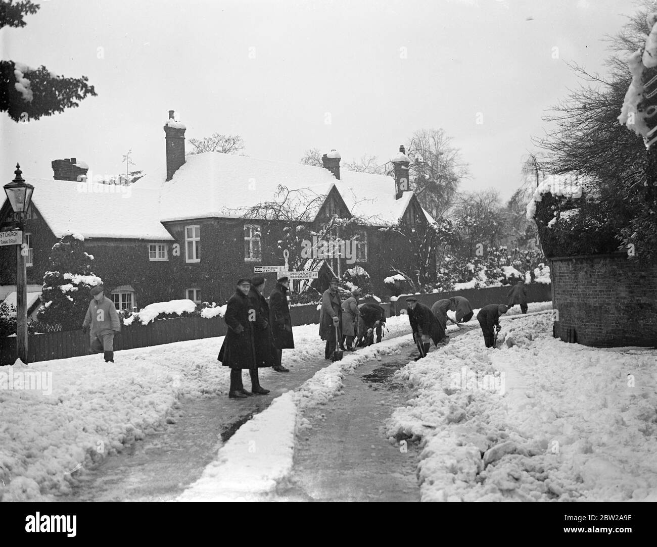 Sgombrare le strade bloccate nell'Hampshire, dopo la bizzarda. Gli squadroni di emergenza sono stati inseriti nell'area di Lyndhurst (Hampshire) per riparare i danni ai fili del telegrafo e per cancellare le strade legate alla neve dopo la terribile bizzarda che ha spazzato il sud dell'Inghilterra. Foto mostra, una banda di operai che liberano la neve dalla collina di Banca bloccata, vicino a Lyndhurst. 8 dicembre 1937 Foto Stock