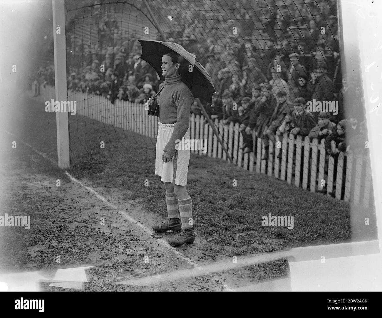 Portiere sotto un ombrello alla partita di calcio tra jokeers e boxers. La partita annuale di calcio di beneficenza tra i più noti pugili e jockey è stata disputata presso il campo di calcio della Millwall, New Cross. Spettacoli fotografici, J Crouch, il fantino del Re, si rifugia dalla pioggia sotto un ombrello, mentre si tiene meta per i jokey. 25 ottobre 1937 Foto Stock