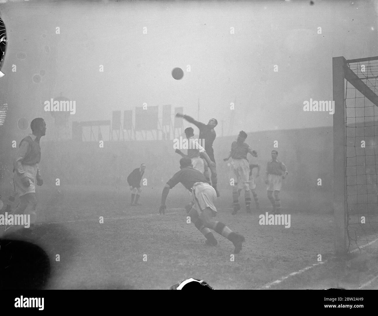 La semifinale della London Challenge Cup giocata in nebbia. Millwall si riserva di soddisfare le riserve dell'Arsenal nella semifinale del London Challenge Cup Competition al Den, New Cross. La partita è stata giocata in nebbia e gli spettatori non potevano vedere le pinze. Foto spettacoli, George Swindon (portiere Arsenale) pugnando la palla. 6 dicembre 1937 Foto Stock