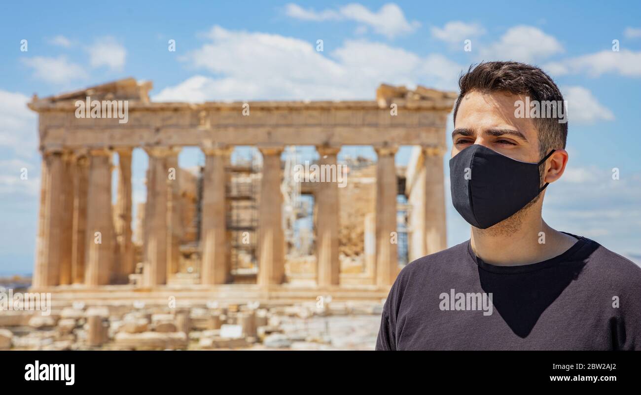 Atene Acropoli, Grecia coronavirus giorni. Giovane uomo che indossa maschera protettiva, antico tempio greco del Partenone e sfondo blu cielo. Foto Stock