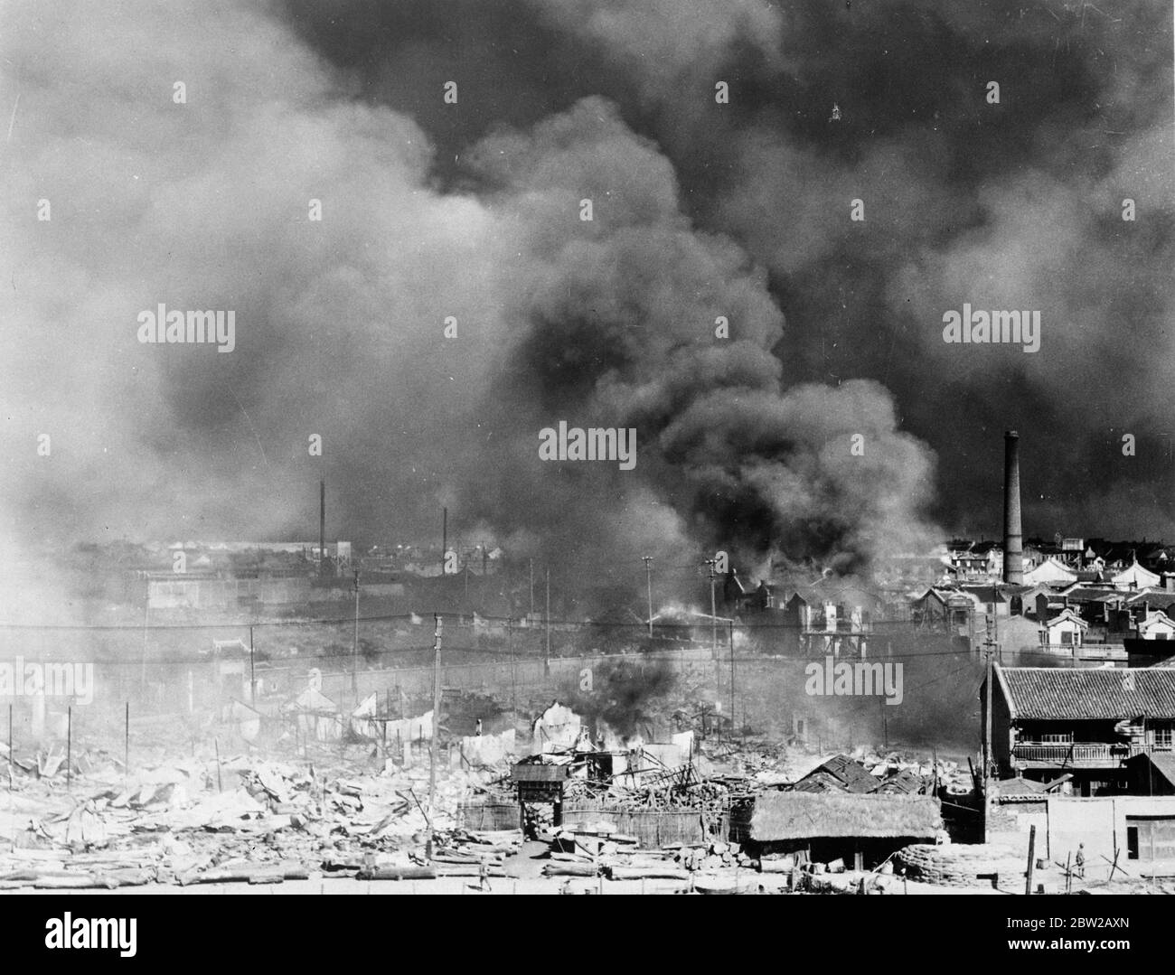 Ritirarsi dai cinesi lascia dietro di loro un muro di fuoco a Shanghai. Martoriato da mesi di bombardamenti e bombardamenti, Chapei, il quartiere cinese di Shanghai, divenne un inferno infuriato quando fu licenziato dalle truppe cinesi mentre si ritirarono prima dei vittoriosi giapponesi. Foto mostra, la palla di denso fumo nero che avvolge le rovine di Chapei come i cinesi ritirati. 1 dicembre 1937 Foto Stock