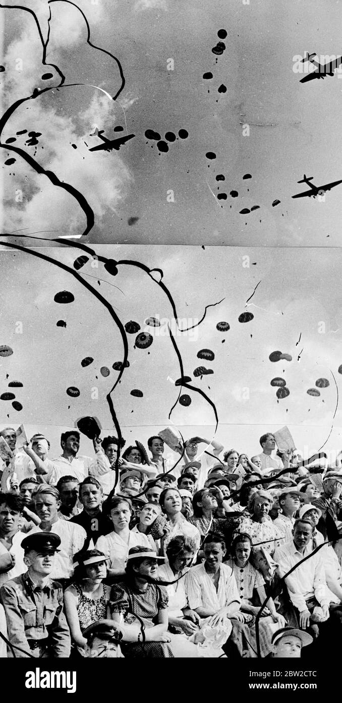 Soldati sovietici galleggiano sulla terra sopra la folla durante un salto di massa paracadute che è stato una caratteristica della mostra al giorno sovietico dell'aria. Joseph Stalin, che causa la costernazione mondiale con il suo patto proposto con la Germania, guardò con 1 milione di persone come bombardieri e combattenti dell'aeronautica sovietica impegnati in una guerra imitazione sull'Aerodromo di Tushino, Mosca. 23 agosto 1939 Foto Stock