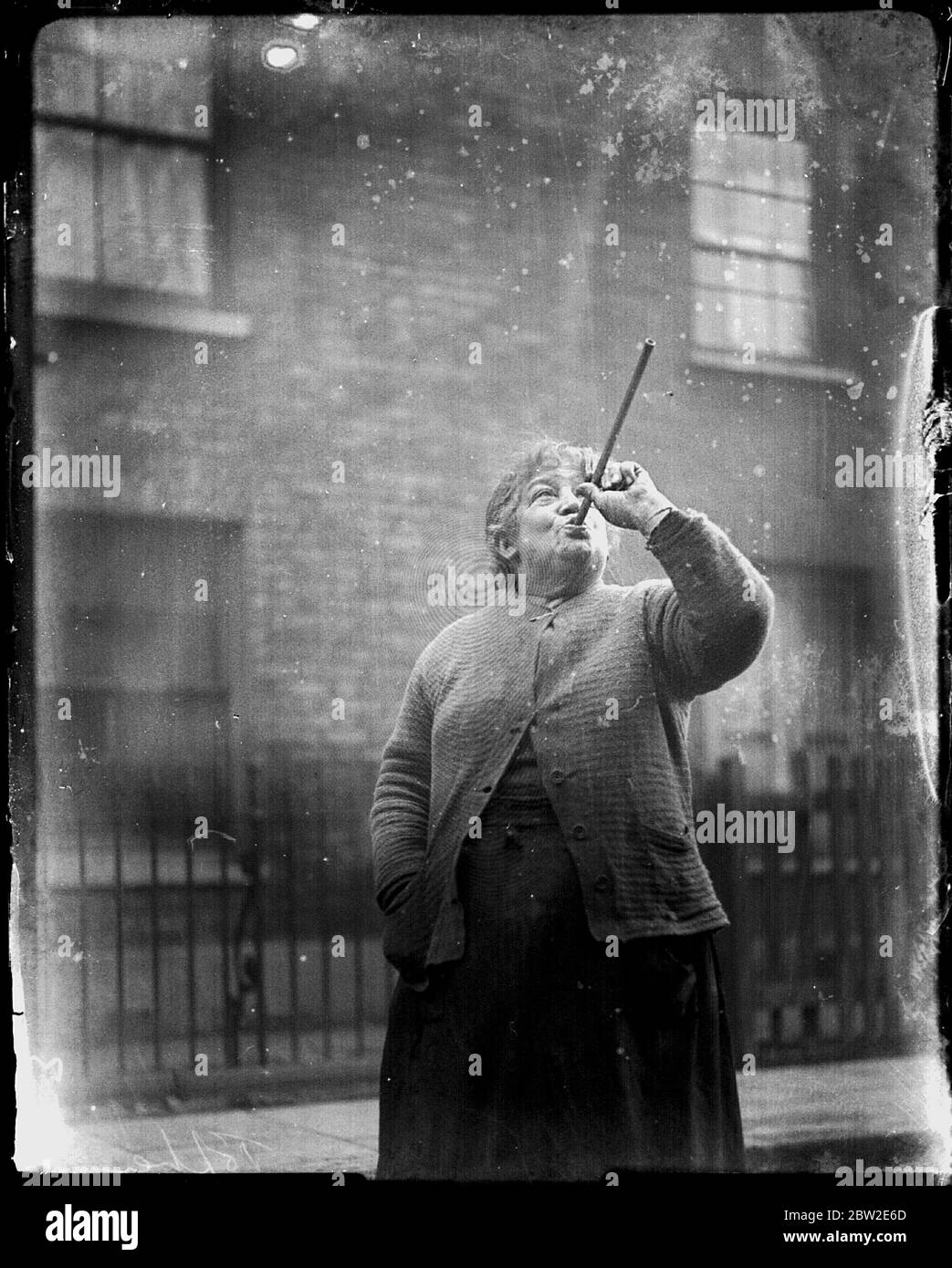 Pochi lavoratori possedevano sveglie, quindi i servizi di questo "knocker up" (Mary Smith) erano in richiesta. I suoi clienti sono stati vagabati sparando piselli alle loro finestre. East End London, 1927 Foto Stock