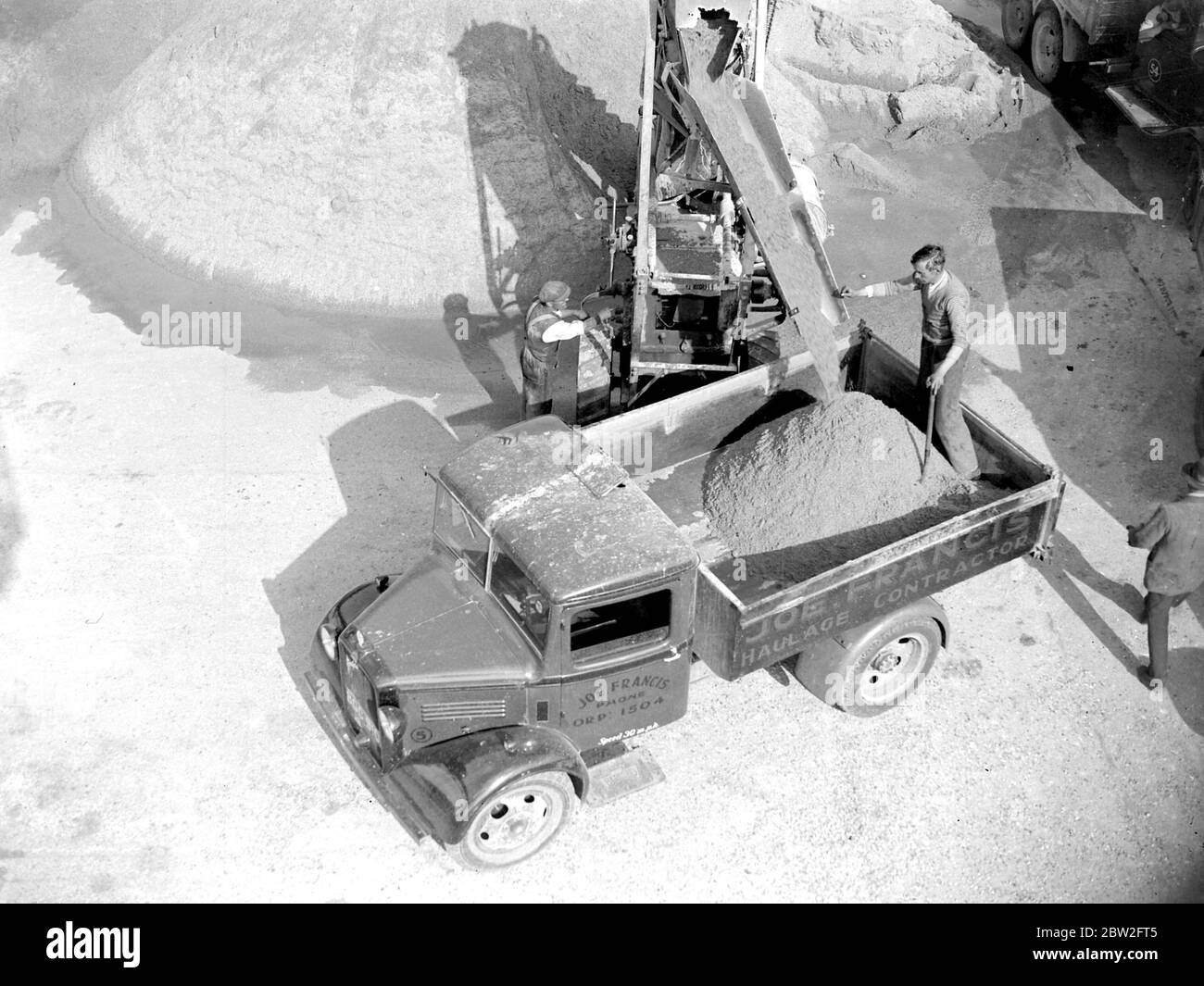 Il dumper Bedford viene caricato da un caricatore trasportatore presso la fossa grigia Sand & Gravel Co Ltd a Sidcup, Kent. 1934 Foto Stock