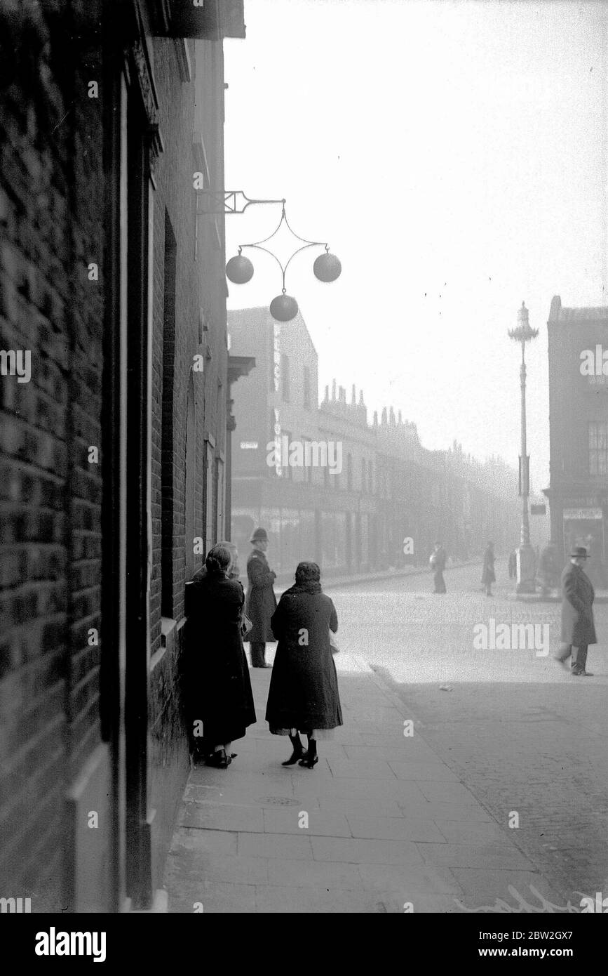 UK London Women aspetta fuori un pawnbroker per aprire un Lunedi mattina nel East End. Un'indagine del tempo ha trovato che una famiglia su tre userebbe il pawnbroker. Circa 1930 Foto Stock