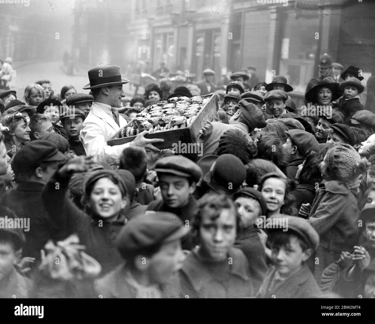 Distribuzione gratuita di focacce di croce calda ai bambini poveri a Fetter Lane, Londra da parte di un macellaio locale. 30 marzo 1923 Foto Stock
