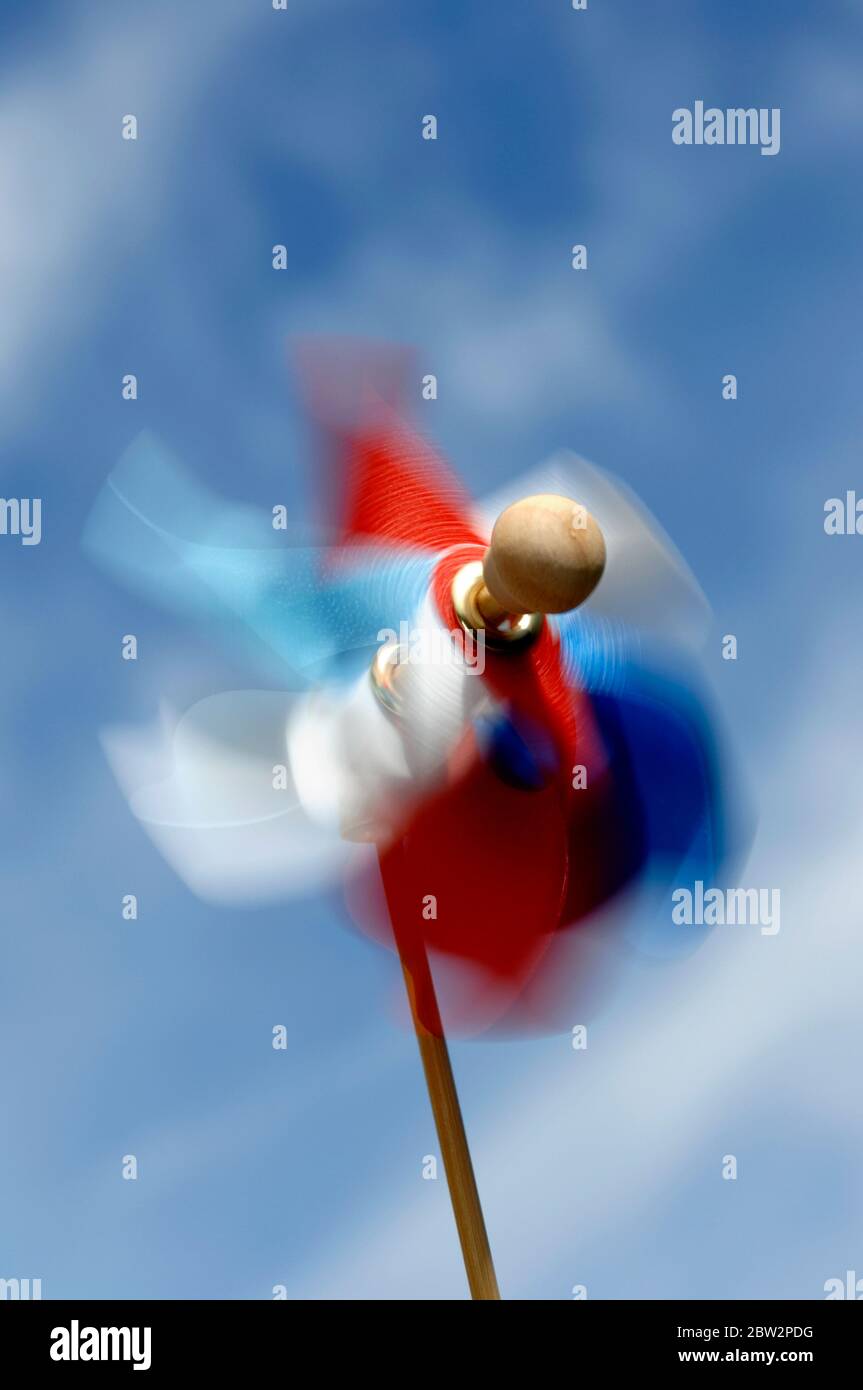 Un mulino a vento rosso bianco e blu a ruota a spillo che soffia nel vento Foto Stock