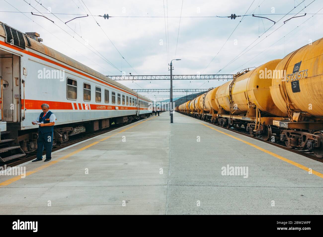 Un treno passeggeri e un treno merci liquido inattivo alla piattaforma della stazione a Gori, Georgia Foto Stock