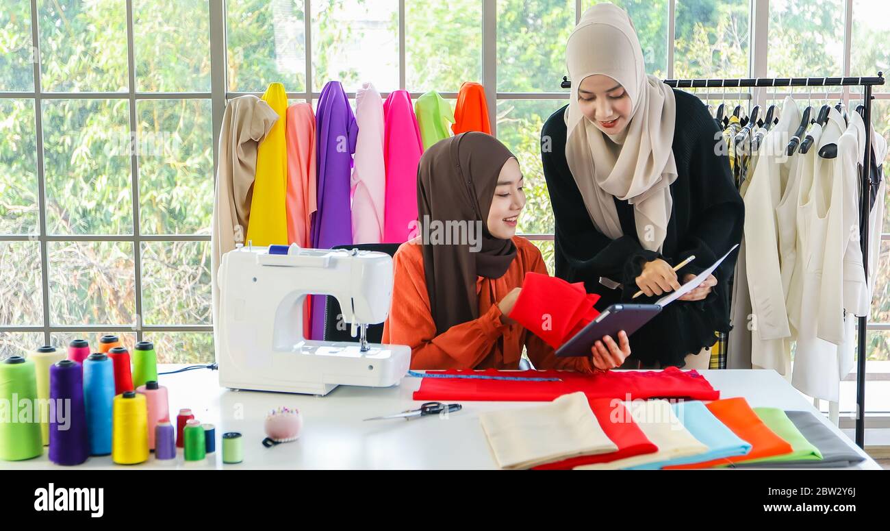 Piccola impresa di designer di moda donna musulmana Che Lavora e utilizza smartphone e tablet Con abiti al negozio di abbigliamento Foto Stock