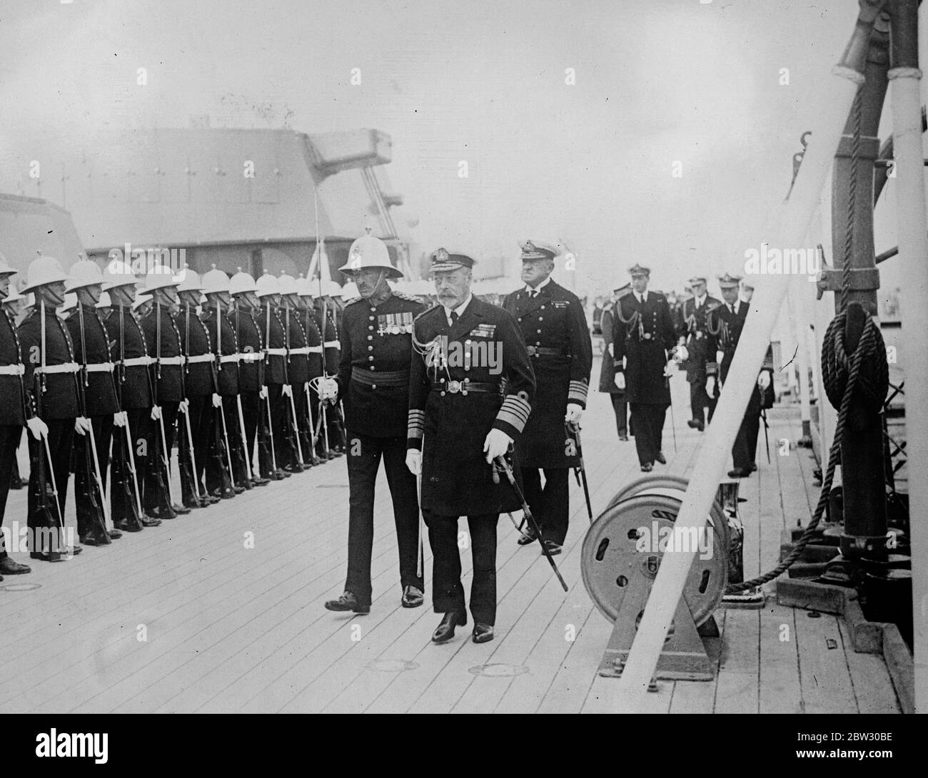 Re ispeziona i marines a bordo della HMS Nelson durante la visita alla flotta di Home a Weymouth . Il re che sta trascorrendo quattro giorni a bordo del suo yacht Victoria e Alber visitando la flotta al largo di Weymouth , accompagnato dal principe di Galles e il principe Giorgio ispezionarono i Royal Marines a bordo della HMS Nelson . Il re che ispeziona i marines a bordo della HMS Nelson sullo sfondo è il Principe di Galles e il Principe Giorgio . 12 luglio 1932 Foto Stock