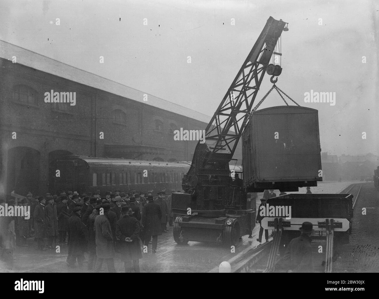 Miglioramenti ferroviari ispezionati sui bracci dei muratori . Nuova crance mobile in azione per la prima volta . Una nuova gru mobile per il sollevamento di carrelli è stata presentata per la prima volta quando i rappresentanti del settore hanno ispezionato i miglioramenti sulla ferrovia meridionale e la ricostruzione del deposito di armi per muratori , che era originariamente il capolinea della ferrovia . Fu qui che la regina Alexandra arrivò per il suo matrimonio con il re Edoardo . La nuova gru mobile in corso di dimostrazione presso il deposito . 8 marzo 1932 Foto Stock