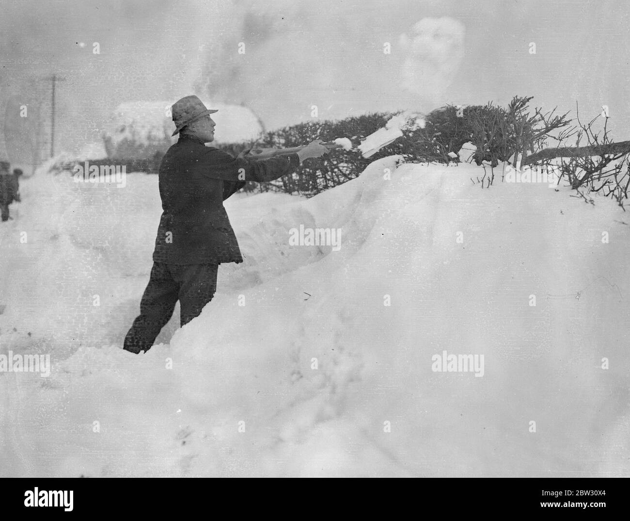 Drifts di neve quattro piedi di profondità blocco Surrey strade al traffico . Derive di neve più di quattro piedi in profondità hanno bloccato le strade in Surrey e Kent e le hanno rese impassabili al traffico , eserciti di uomini sono al lavoro di sgombero le strade . Sgombrare la neve su una strada a Tatsfield , Surrey , dove le derive sono più di quattro piedi di profondità . 13 febbraio 1932 Foto Stock