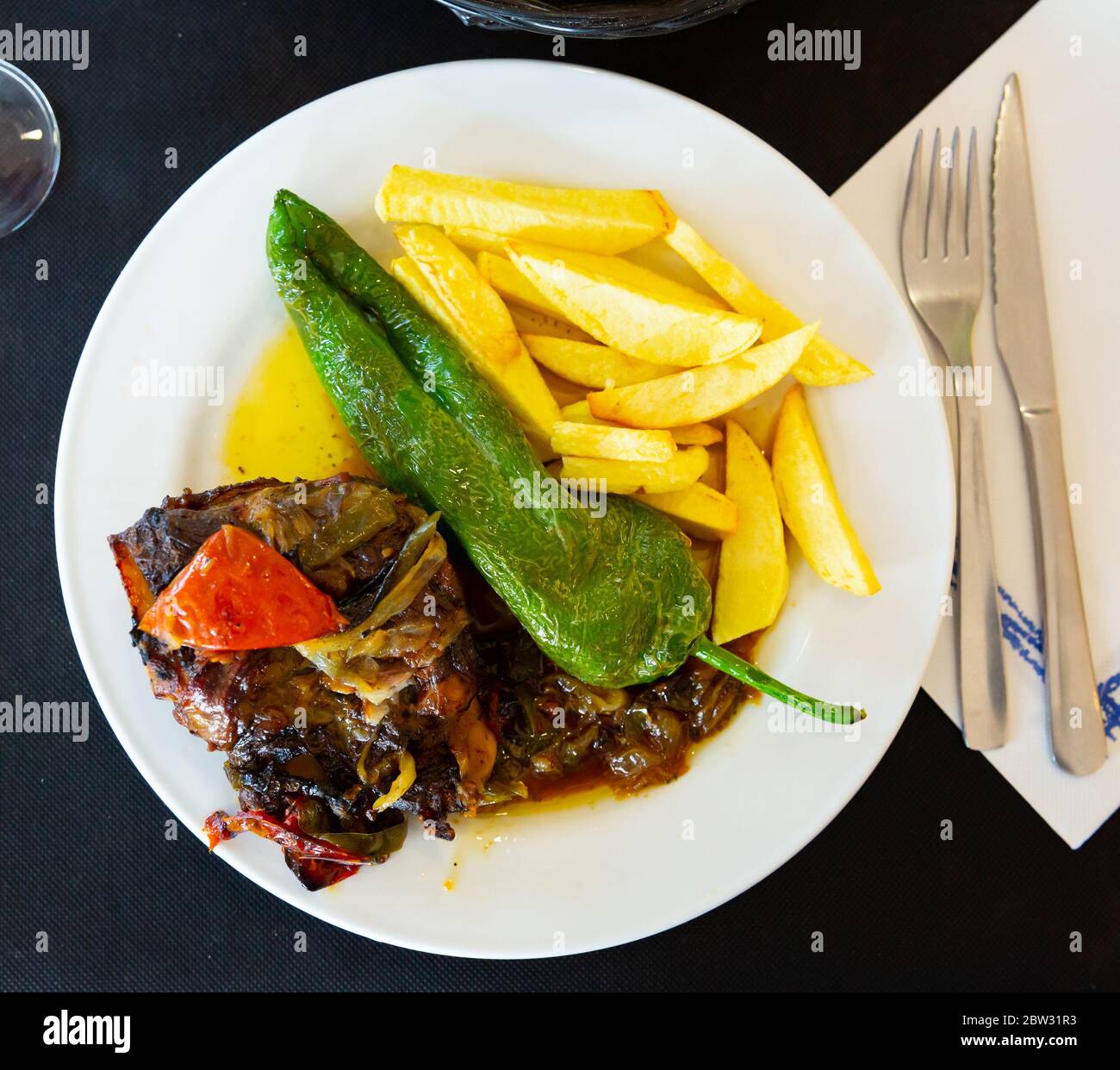 Gustose guance di maiale stufate con sugo di verdure, patate fritte e pepe verde al forno Foto Stock