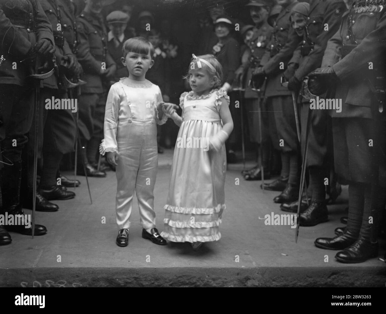 Matrimonio militare presso i minuscoli assistenti nuziali di Sant'Ethelburga . Il matrimonio del maggiore William le Hardy secondo al comando del 23° Reggimento londinese, un agente discale, E l'editordelle calandre dei paesi di Middlesex , Hertford , Buckingham e Essex , a Miss Elizabeth Tuckett , si è svolto nella chiesa di St Ethelburga , Bishopsgate , Londra . Due piccoli assistenti nuziali che lasciano la chiesa dopo la cerimonia 24 settembre 1932 Foto Stock