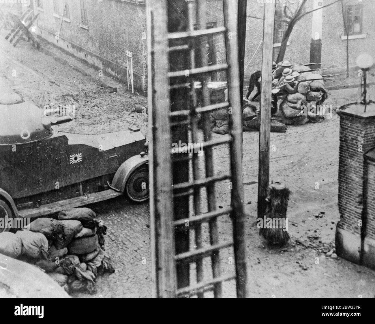 Rinforzata da un'auto blindata , le truppe giapponesi sono viste sparare dietro le barricate del sandbag a Shanghai il 26 febbraio 1932 Foto Stock