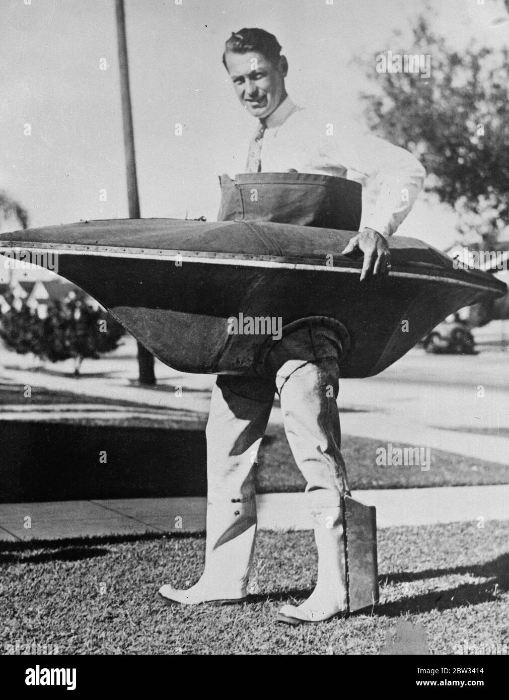 Uomo in barca anatra a piedi per attraversare il canale di catalina . Cecil Carmichael con la sua casa fatto a piedi anatre barca piani per camminare il canale dalla terraferma d'America a Catalina Island . La distanza è di 25 minuti . La barca è lunga 6 piedi e larga 3 piedi. E' realizzato in impiallacciatura di pioppo e rivestito di tela. Gli stivali in gomma sono fissati alla parte inferiore dell'imbarcazione per le gambe dell'operatore . Le alette di rame sono fissate alle cuffie per eliche . La barca è progettata per la caccia e la pesca d'anatra. Non può capsise e pesa soltanto 50 libbre completo . Cecil Carmichael e la sua barca d'anatra a piedi . 15 aprile 1932 Foto Stock