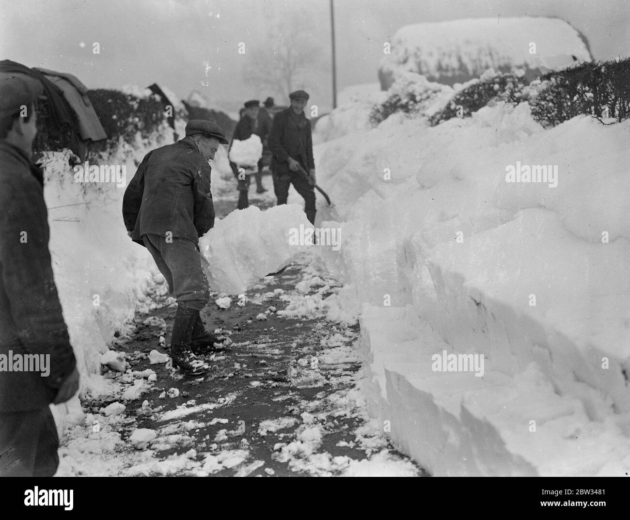 Drifts di neve quattro piedi di profondità blocco Surrey strade al traffico . Derive di neve più di quattro piedi in profondità hanno bloccato le strade in Surrey e Kent e le hanno rese impassabili al traffico , eserciti di uomini sono al lavoro di sgombero le strade . Facendo un passaggio difficile attraverso una neve deriva quattro piedi profondo in una strada a Tatsfield , Surrey . 13 febbraio 1932 Foto Stock