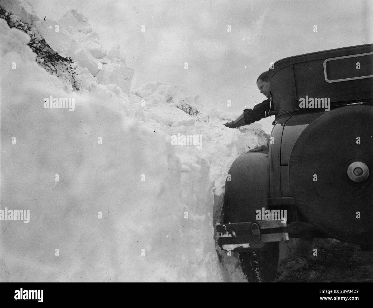 Drifts di neve quattro piedi di profondità blocco Surrey strade al traffico . Derive di neve più di quattro piedi in profondità hanno bloccato le strade in Surrey e Kent e le hanno rese impassabili al traffico , eserciti di uomini sono al lavoro di sgombero le strade . Neve su una strada a Tatsfield , Surrey , che mostra quanto profonda è confrontata con la macchina che attraversa . 13 febbraio 1932 Foto Stock