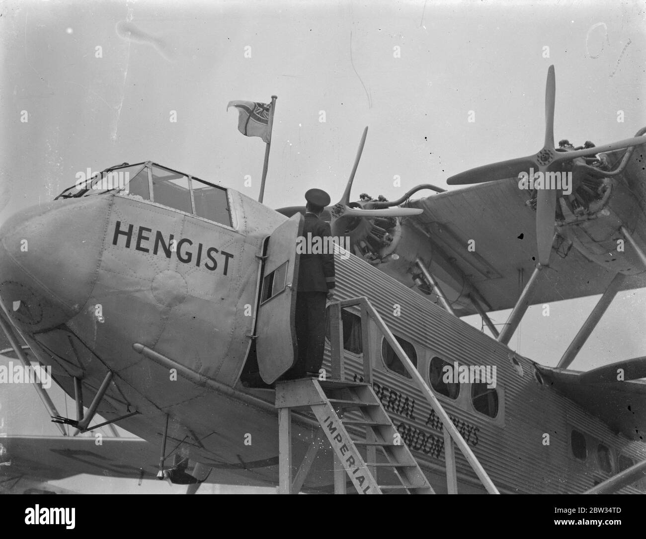 Nuova bandiera dell'aviazione civile britannica issata a Croydon . La nuova bandiera britannica dell' aviazione civile, costituita dalla croce di St George , con l' Unione Jack nel corn che è issata su un aereo imperiale , all' Aerodromo di Croydon , Londra , prima di partire per Aintree , Liverpool che trasporta passeggeri per vedere il Grand National . 18 marzo 1932 Foto Stock