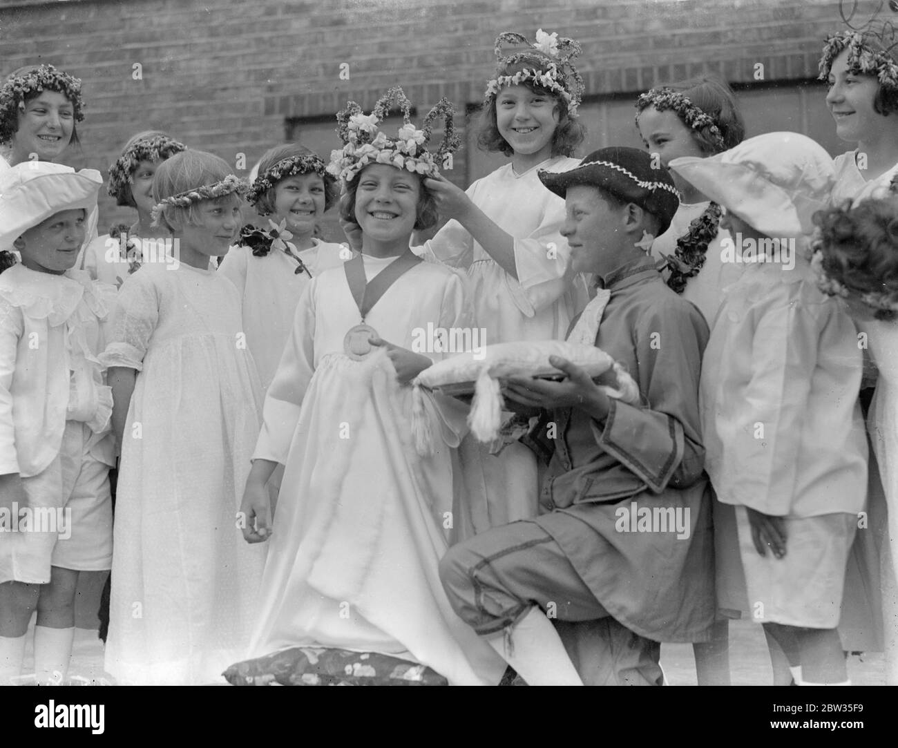 Primo maggio Regina dell'anno incoronata a Dagenham . La Dagenham May Queen , il primo dell' anno , fu incoronata nella Osborne Hall di Dagenham . La nuova Regina , Olive Smith , di 10 anni , fu incoronata dalla vecchia regina Patricia cane di 12 anni . La vecchia regina Patricia cane incorona la nuova regina di Dagenham Olive Smith . 29 aprile 1933 Foto Stock