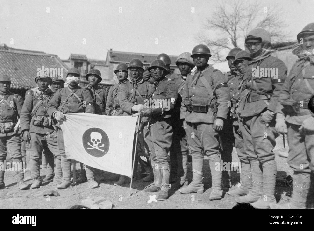 La compagnia principale giapponese della morte occupa Kupeikou . La celebre compagnia giapponese Death's Head , altrimenti conosciuta come la Compagnia Dokurotai , guidata dal tenente Ikegami , che porta la loro famosa bandiera con il disegno del cranio e delle ossa incrociate , diresse truppe cinesi nel distretto di Jehol e catturò la città di Kupeikou . Il tenente Ikegami capo della compagnia della morte con la bandiera della compagnia dopo aver occupato Kupeikou. 26 aprile 1933 Foto Stock
