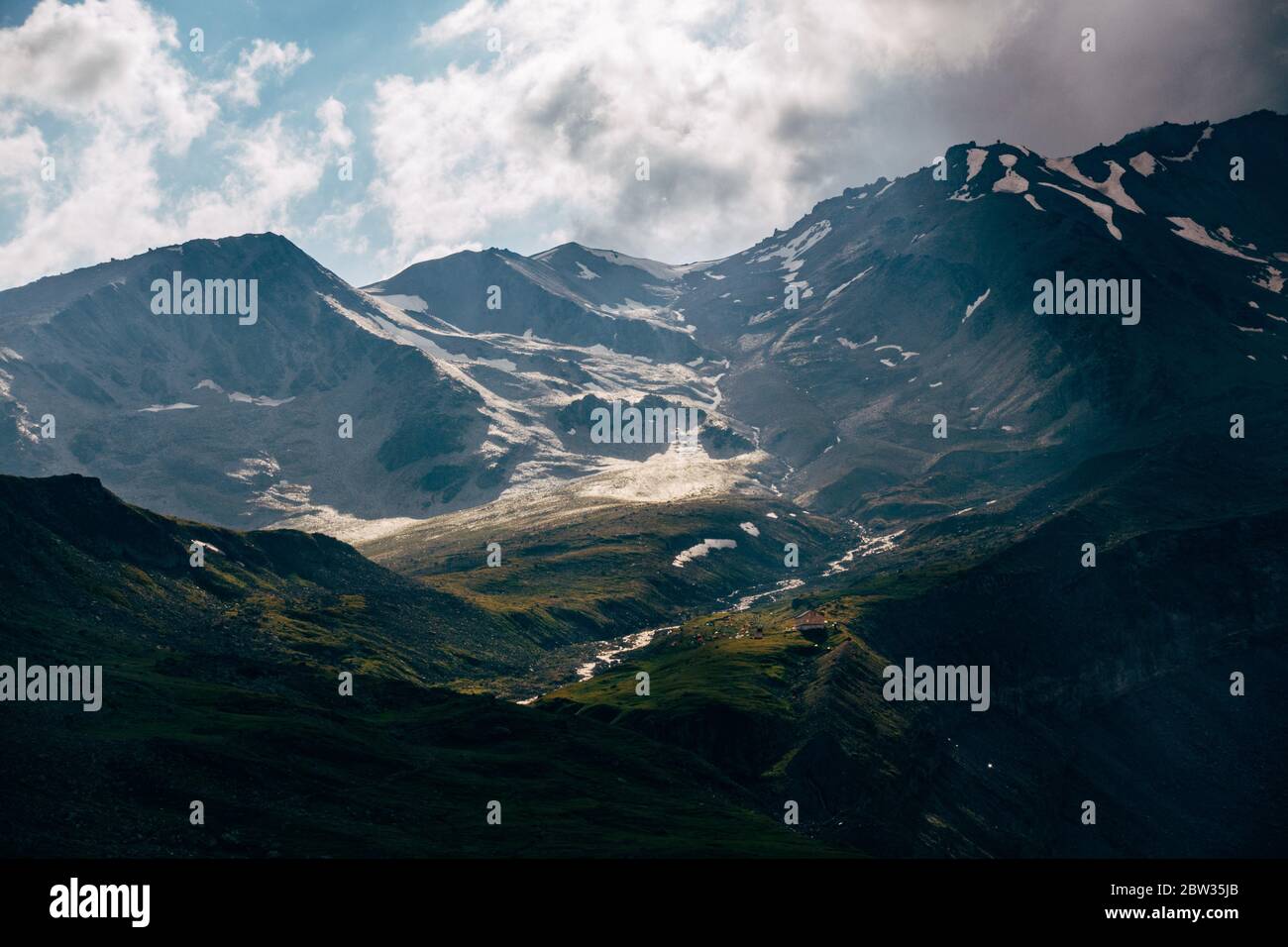 La luce del sole esplode attraverso una nuvola e illumina la neve vicino al Monte Kazbek, Georgia Foto Stock