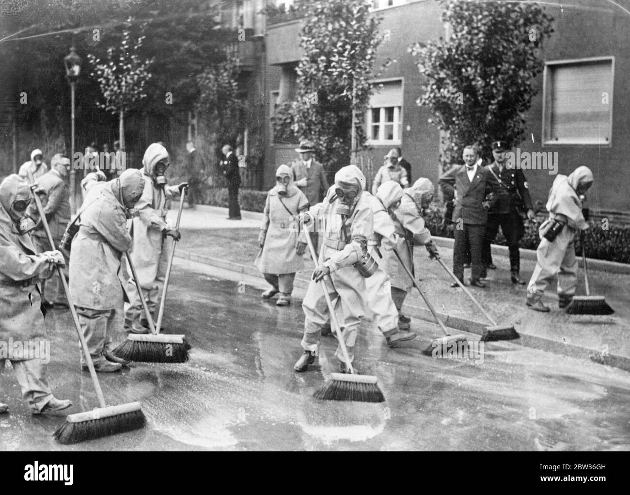 Le strade tedesche saranno pulite come di consueto durante la prossima guerra . Affinché ogni cittadino sappia combattere gli attacchi di gas durante la prossima guerra senza discostarsi dalla sua consueta routine , i lavoratori sono stati tenuti a sottoporsi ad un periodo di formazione nell' uso delle maschere a gas in molte città tedesche. I pulitori di strada che indossavano maschere a gas mentre spazzavano le strade erano uno spettacolo romanzo a Berlino. I pulitori di strada indossavano maschere a gas mentre lavoravano in una strada di Berlino . 19 agosto 1933 Foto Stock
