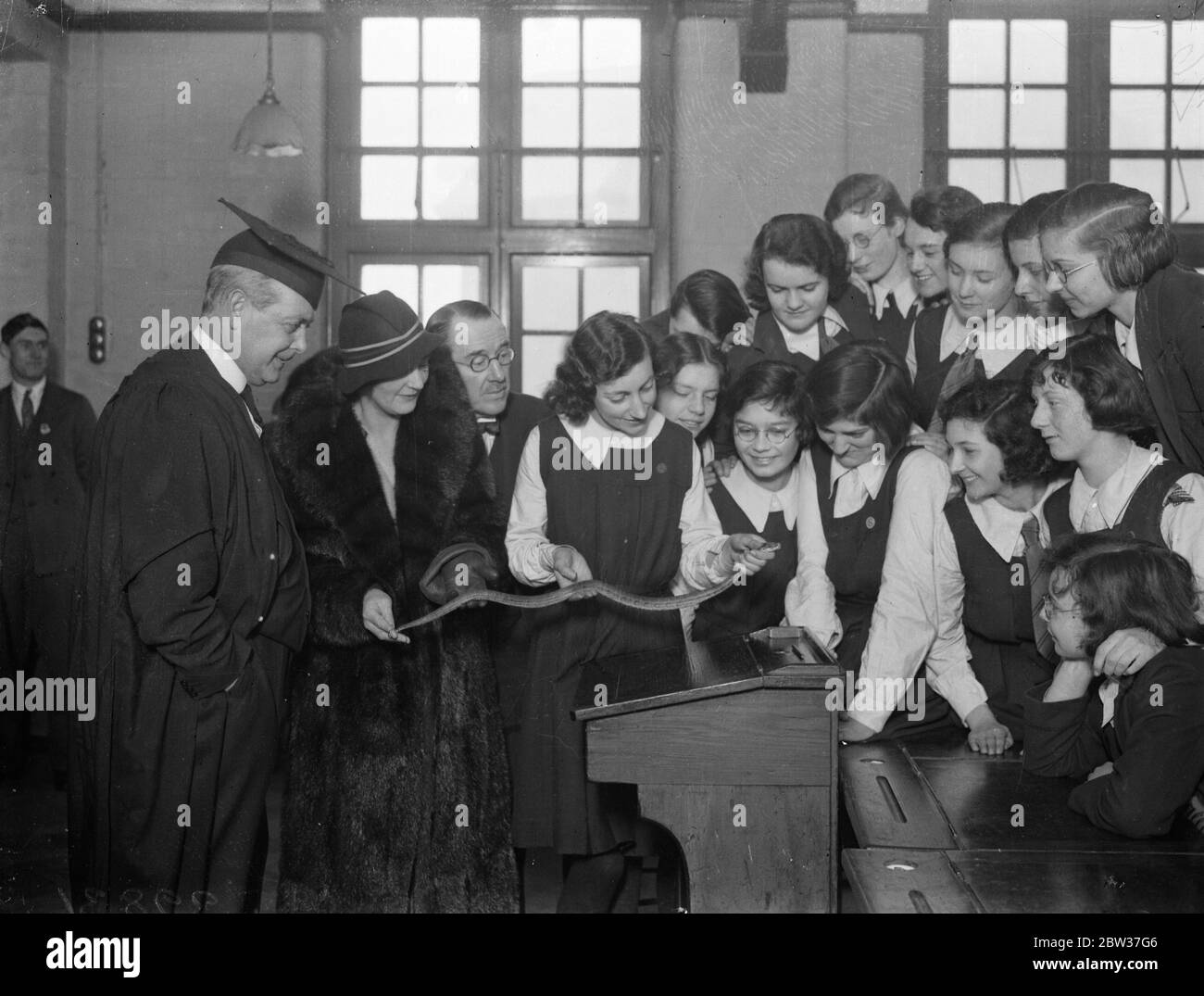 Le ragazze di scuola comprano un python vivo come animale domestico. Ragazze della Trinity County School , , Wood Green , londra sono state presentate con un pitone come un animale domestico , il rettile è lungo tre piedi ma probabilmente crescerà a sei o sette piedi in pochi anni . E' stato presentato loro da Lieut col R H Elliot , il distinto specialista degli occhi , le ragazze hanno sottoscritto alcuni dei costi tra loro e i ragazzi hanno costruito una gabbia di legno per il serpente . La foto mostra la signora Emrys Jones , moglie del direttore della Trinity County School , Woodgreen , amante dei serpenti che mostra alle ragazze come tenerla . 24 gennaio 1934 Foto Stock