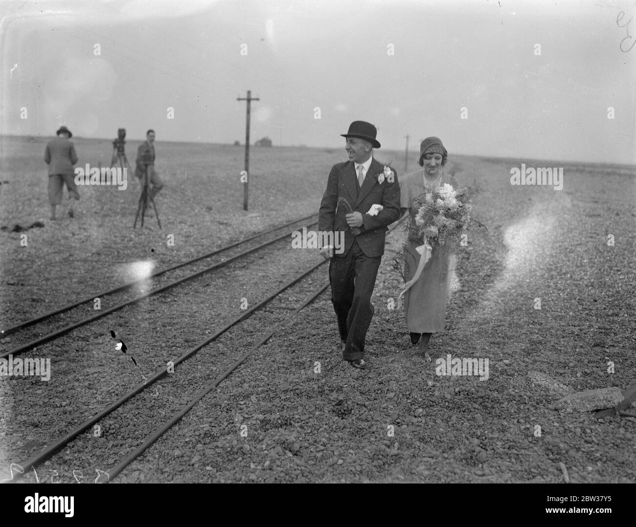 Treno speciale per una sposa . Railway re - aperto per il matrimonio di figlia di pescatore Dungeness . La sposa viaggiò in un treno speciale da e per il suo matrimonio , quando la piccola ferrovia di Lydd , Kent , fu aperta specialmente per il matrimonio di Miss Annie Elizabeth Young , figlia di un pescatore Dungeness e del suo sposo , Ambrose Bingham . L'unico mezzo di trasporto tra la casa di Miss Young e Lydd , distante 3½ chilometri , è la piccola ferrovia , che attraversa due miglia di ghiaia . Spettacoli fotografici ; lo sposo e lo sposo camminano lungo le tracce dopo la cerimonia . 23 dicembre 1933 Foto Stock