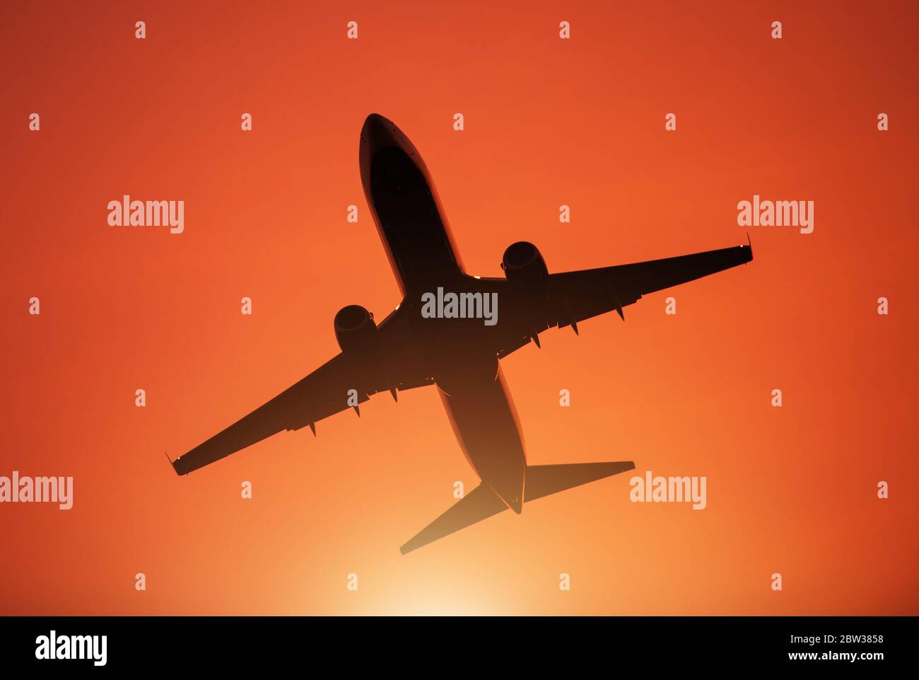 Tema viaggio aereo. Aereo commerciale passeggeri durante il decollo dall'Aeroporto locale. Cielo di tramonto rossastro. Foto Stock