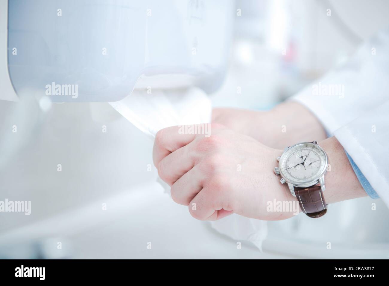 Medico che usa salviette igienizzanti in velluto per pulire le mani. Dispenser di panni. Tema sanitario. Disinfezione delle mani. Foto Stock