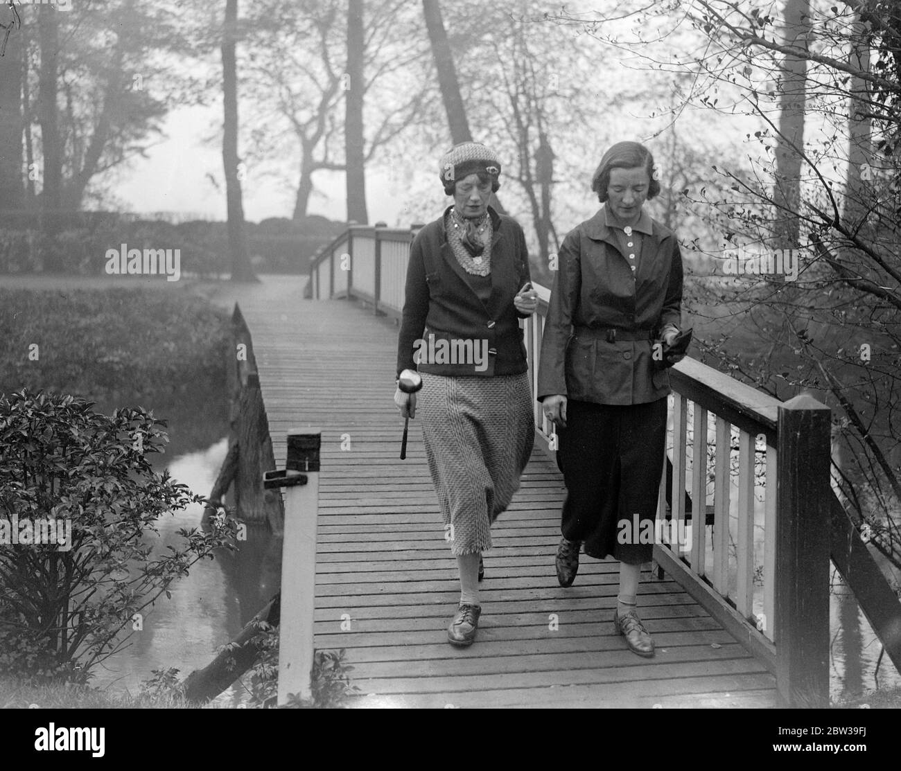 Signore parlamentare golf a Ranelagh . Il club di golf Ladies Parliament ha aperto la sua riunione di primavera al ranelagh Club di Londra . Spettacoli fotografici ; due golfisti lady fanno la strada più sopra il ponte sulla loro strada per il campo da golf . 27 aprile 1934 Foto Stock