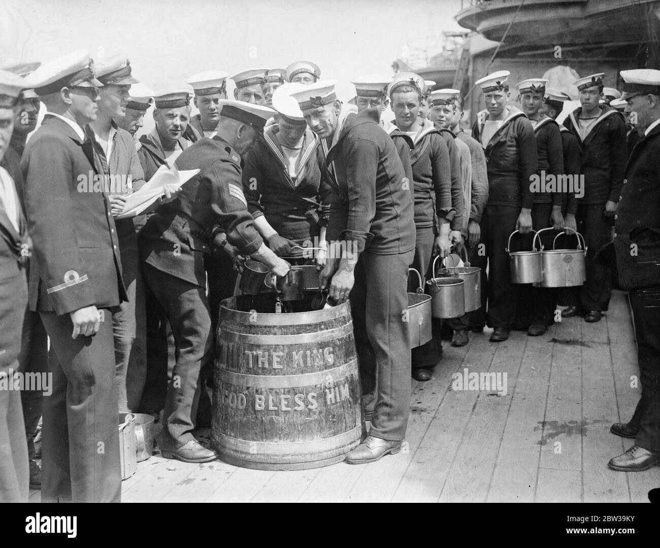 I marinai a bordo di HMS Hood (numero del pentnant 51) si allineano per disegnare la razione del rum in preparazione di bere alla salute del re . 15 luglio 1935 Foto Stock