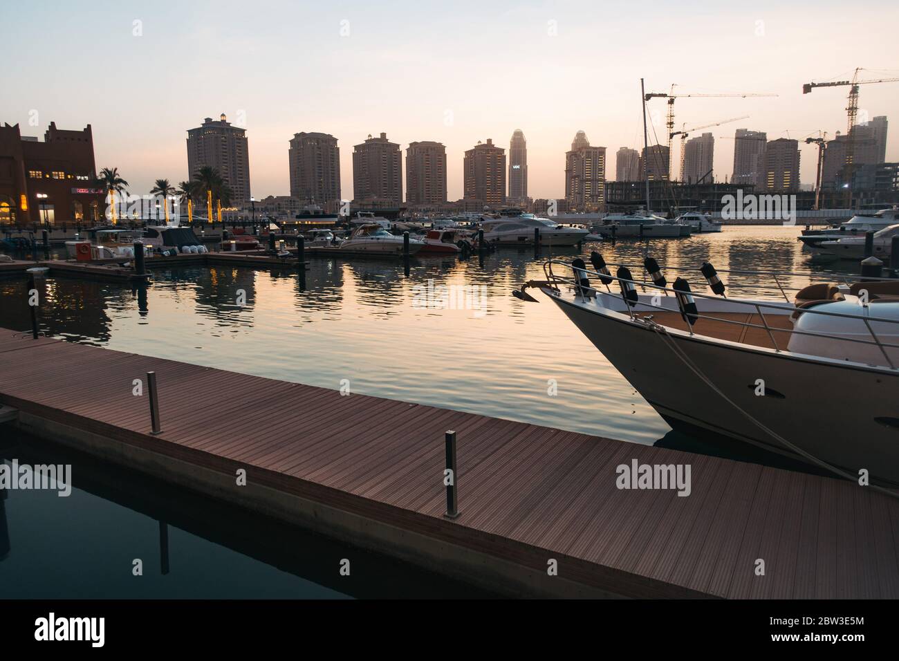 Potrai fare un tramonto lungo il lungomare del porticciolo presso il Pearl-Qatar, un'isola residenziale artificiale a Doha, Qatar. L'isola di Marsa Arabia è vista in costruzione Foto Stock