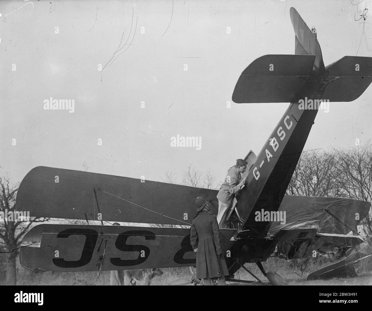 Aereo , pilotato da 22 anni Londoner colpisce l'albero e si schianta in campo in Essex . Il signor John Everett Ray , il pilota , esamina il suo aereo danneggiato . 19 marzo 1935 Foto Stock