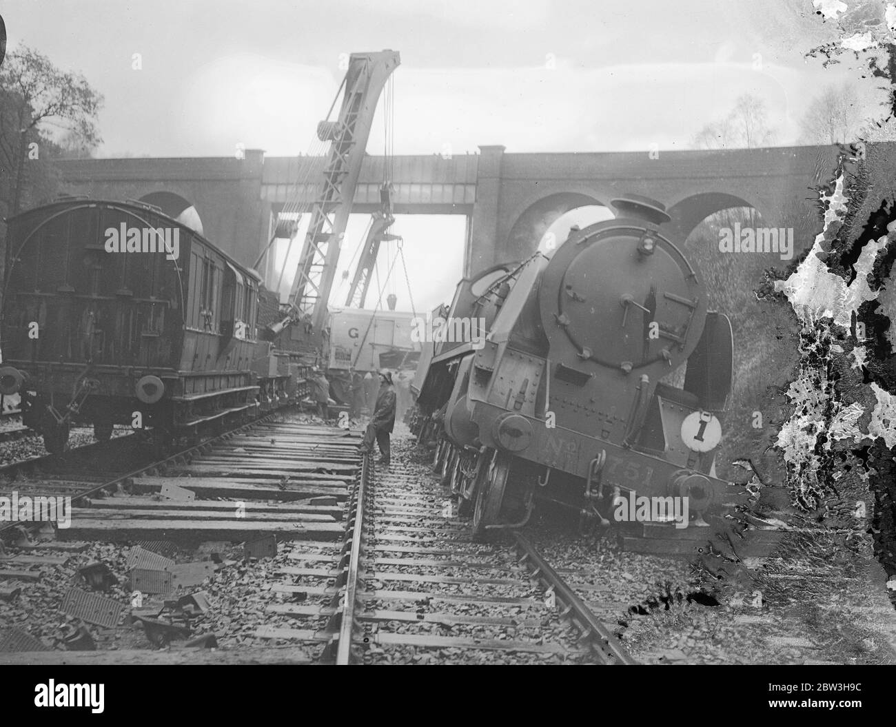 Treno naufragato da frana nell' Hampshire . Centinaia di tonnellate di terra e roccia , che si credeva fossero state allentate dalle forti piogge , che si sono abbattute fino alla linea ferroviaria, hanno completamente distrutto un treno di latte vicino a Winchfield , tra Fleet e Hook , Hampshire . Tutte le piste sono state bloccate e il traffico ferroviario è stato interrotto . I gruppi di guasti stanno lavorando per eliminare le linee . Foto mostra , il motore deragliato del treno del latte , con il camion relitto sullo sfondo . 17 novembre 1935 Foto Stock