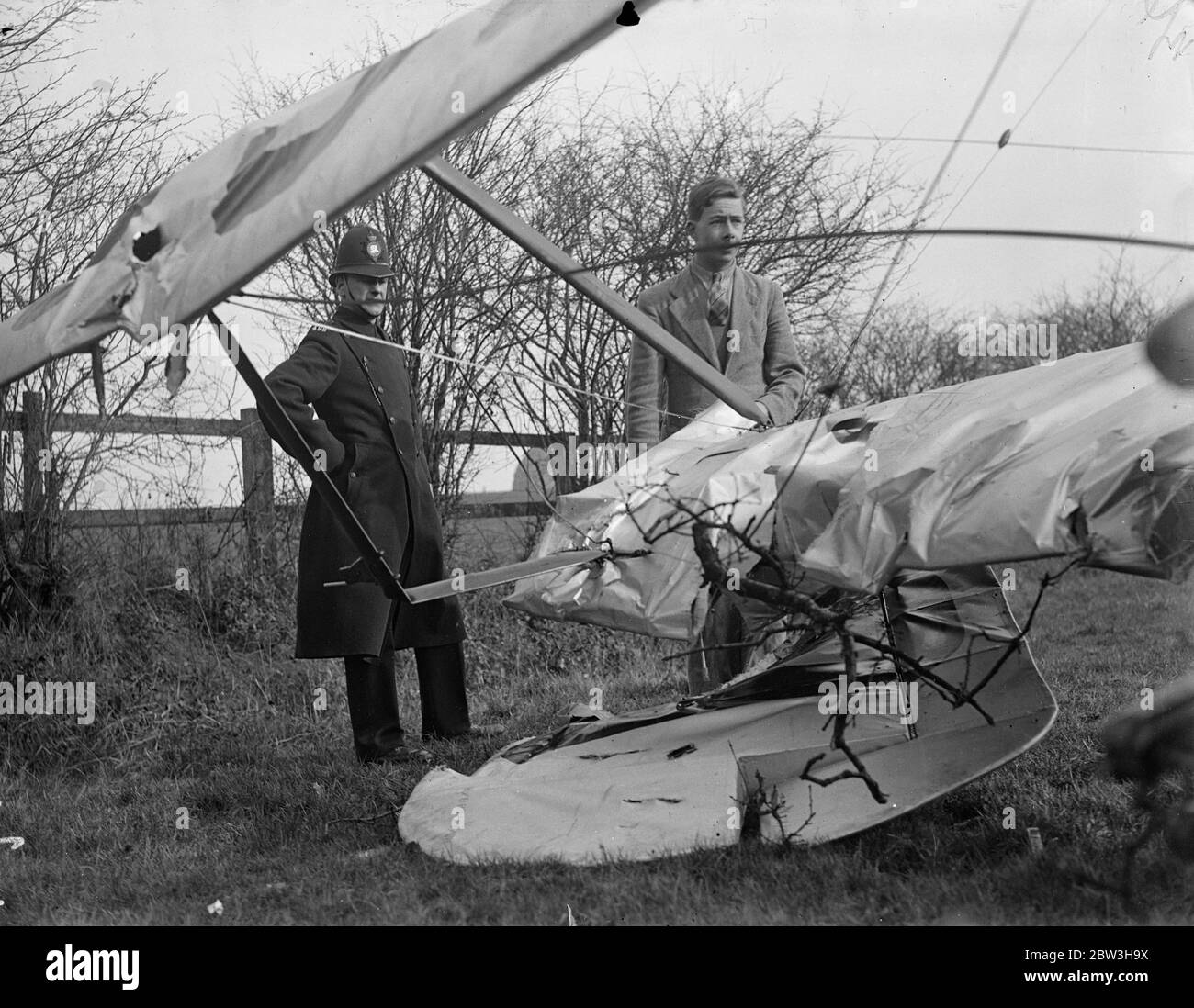 Aereo , pilotato da 22 anni Londoner colpisce l'albero e si schianta in campo in Essex . Il pilota, John Everett Ray , guarda nel pozzetto del suo aereo danneggiato . 19 marzo 1935 Foto Stock