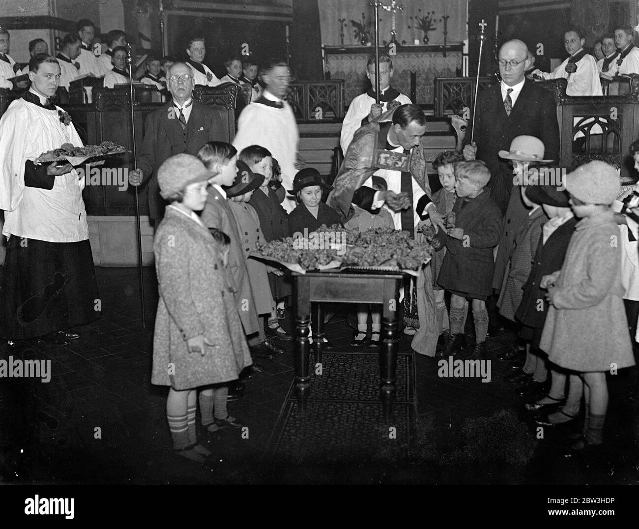 Il Vicario , don B G Chandler porgendosi le violette ai bambini per la ridistribuzione alle madri nella domenica di maternità . 22 marzo 1935 Foto Stock