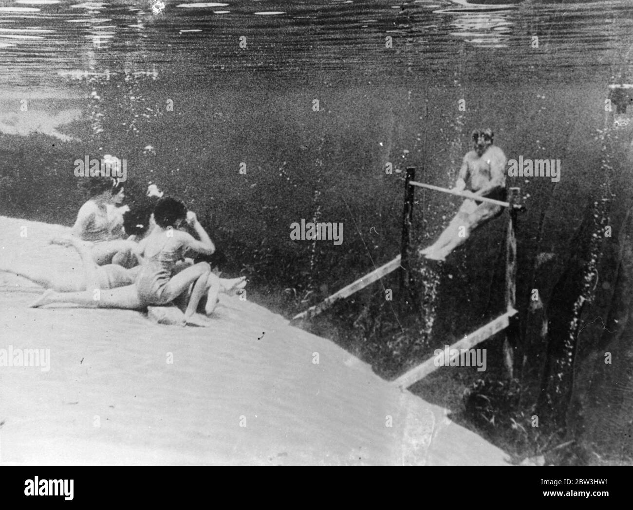 Queste immagini, alcune delle più insolite mai fatte, sono state scattate sotto il mare a Silver Springs, Florida, dove, tra i pesci molto colorati e i fronti ondulati delle piante sottomarine, la scuola più strana del mondo è stata stabilita sulle sabbie del fondale marino. Banchi di scuola , un tavolo di maestro e persino dunces sgabello alto sono stati presi sotto la superficie per la scuola , l'idea di un produttore che voleva un nuovo angolo per un fil che gli allievi, tutti i nuotatori esperti, anche eseguire una palestra per la ricreazione sotto le onde . Foto mostra, i membri della classe guardando un display su una barra orizzontale nel und Foto Stock