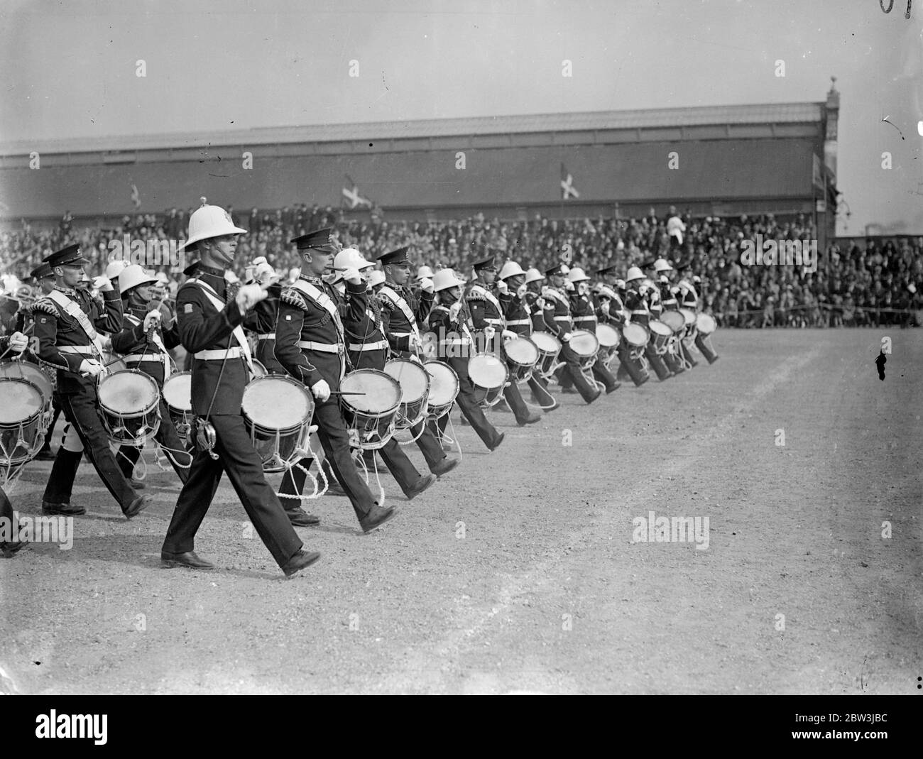 Musica su marzo . Prove di bande massaggiate per il torneo Royal . Tamburi battendo e caschi bianchi che scintillano le bande massaggiate dei Royal Marines a Portsmouth con i 2 Battaglione Regiment Regiment Regiment regna le prove finali per il Royal Tournament , che apre ad Olympia giovedì 7 maggio . Spettacoli fotografici , le bande massaggiate dei Royal Marines e i 2 Battaglione Regiment Regiment Registi reali marciando nell'arena durante una mostra a Whale Island . Porstmouth , che ha svolto come prova di vestiista per il Royal Tournament . 5 maggio 1936 Foto Stock