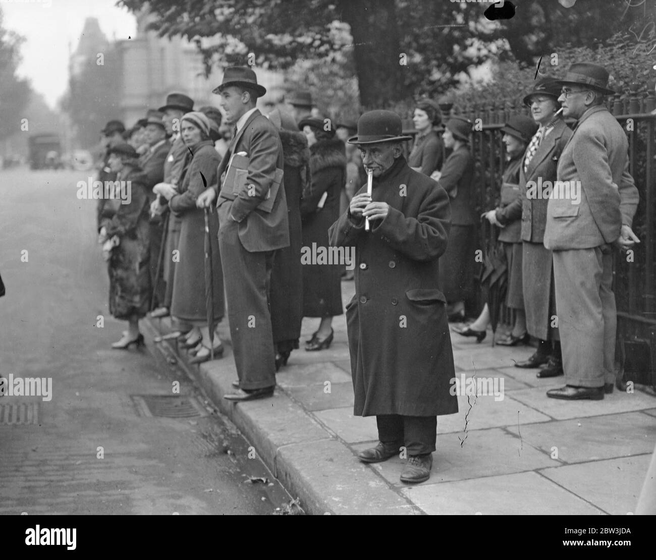 Il musicista di strada intrattiene la folla a Piazza Belgrave No 3. Il latta whistler che gioca alla folla fuori da Piazza Belgrave No 3 . 9 ottobre 1935 Foto Stock