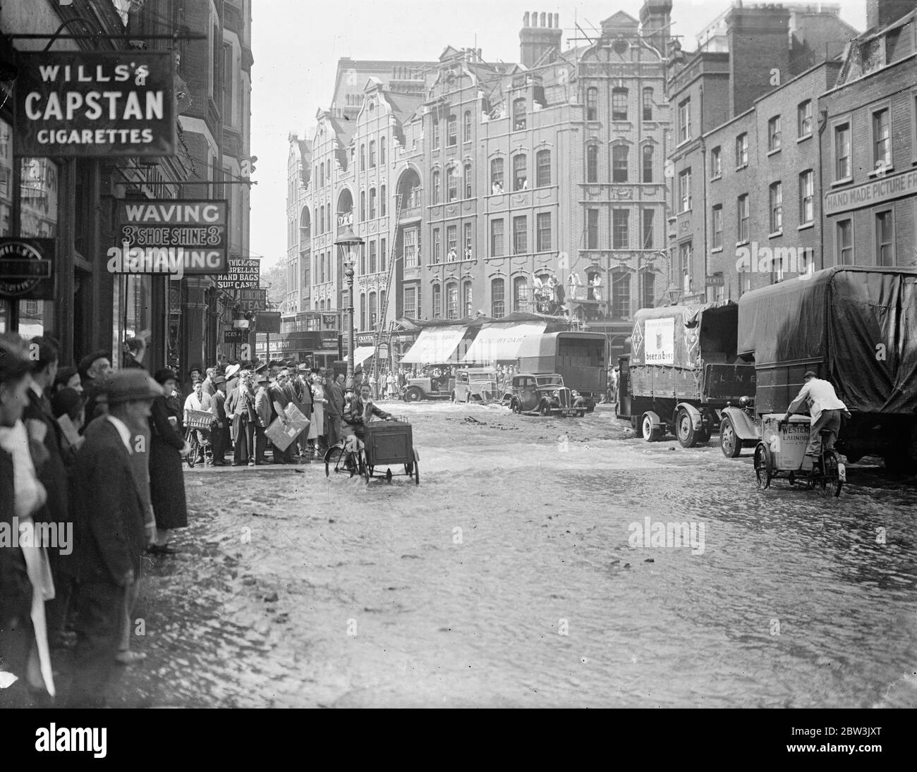 La strada di Theobald è stata trasformata in un fiume dallo scoppio principale dell'acqua . La strada di Theobald fu allagata da Bloomsbury a Holborn da un grande scoppio d'acqua al Bloomsbury End . La superficie della strada era gravemente danneggiata e il traffico inviava docce di spray mentre si schizzava attraverso l'acqua conosciuta a Londra per molto tempo . Spettacoli fotografici , la strada di Theobald trasformata in un fiume dallo scoppio . 17 giugno 1936 Foto Stock