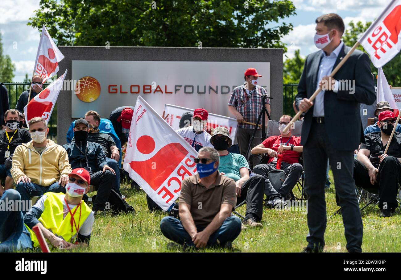 Dresda, Germania. 29 maggio 2020. I dipendenti si siedono e si levano in piedi a intervalli davanti al cancello della fabbrica del produttore di chip di Dresda Globalfondries durante un attacco di avvertimento, indossando boccagli e bandiere dell'IG BCE. Il sindacato IG Bergbau, Chemie, Energie, Landesbezirk Nordost, si sta impegnando per un contratto collettivo, inizialmente attraverso un contratto collettivo di società. Credit: Robert Michael/dpa-Zentralbild/dpa/Alamy Live News Foto Stock