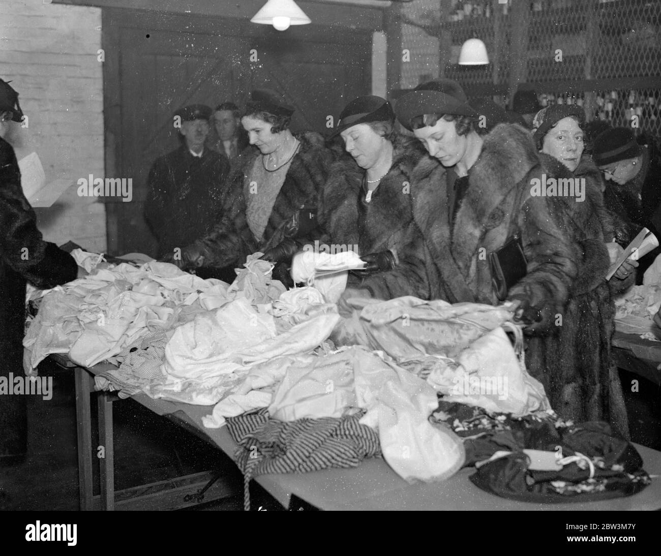 I cacciatori di affare affollano i bacini di Southampton prima dell'asta annuale delle merci dutiable. Centinaia di donne hanno affollato il magazzino del Re ai Docks di Southampton per esaminare le merci esposte al pubblico prima della vendita annuale all' asta di merci dutibili sequestrate o cedite alla dogana. Gli articoli visualizzati includono abbigliamento , profumi , liquori , vini e valvole wireless . Foto , donne rivestite di pelliccia che esaminano le sete alla vista del pubblico prima della vendita al magazzino del Re . 4 dicembre 1935 Foto Stock
