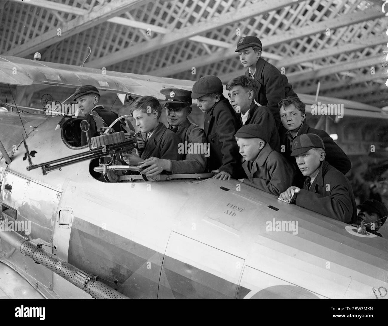 Gli studenti indagano sulle opere di un aereo da combattimento in Empire Air Day a Hendon . Grandi folle , tra cui molti bambini , hanno guardato l'esposizione Empire Air Day all'Hendon Aerodrome . L'11° Reggimento londinese (The Finsbury Frifles ) , che ora comprende le batterie degli aerei 171 e 170, ha collaborato con la Royal Air Force in mostra . Foto , studenti che sperimentano con l'anello di pistola Lewis in un Hawker Demon Fighter . 23 maggio 1936 Foto Stock