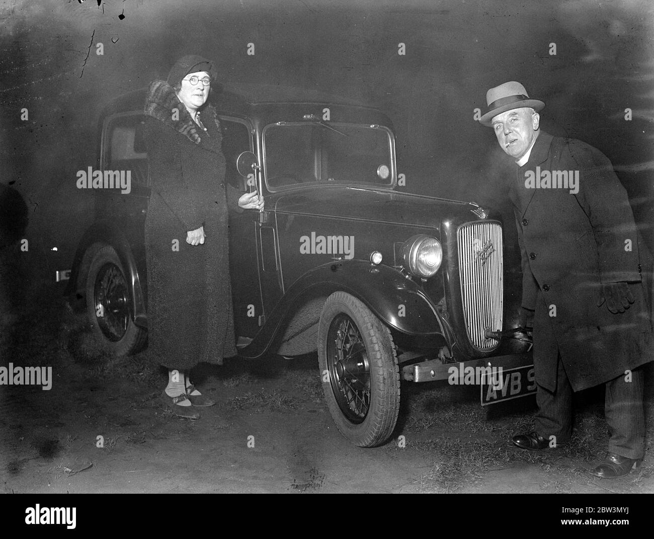 L'uomo della città dà l'automobile al Vicario di Coster di St Mary Maddalene , Old Kent Road . Il Rev A Barker che avvia il motore della sua auto . Anche nella foto è la signora Barker . 7 dicembre 1935 Foto Stock