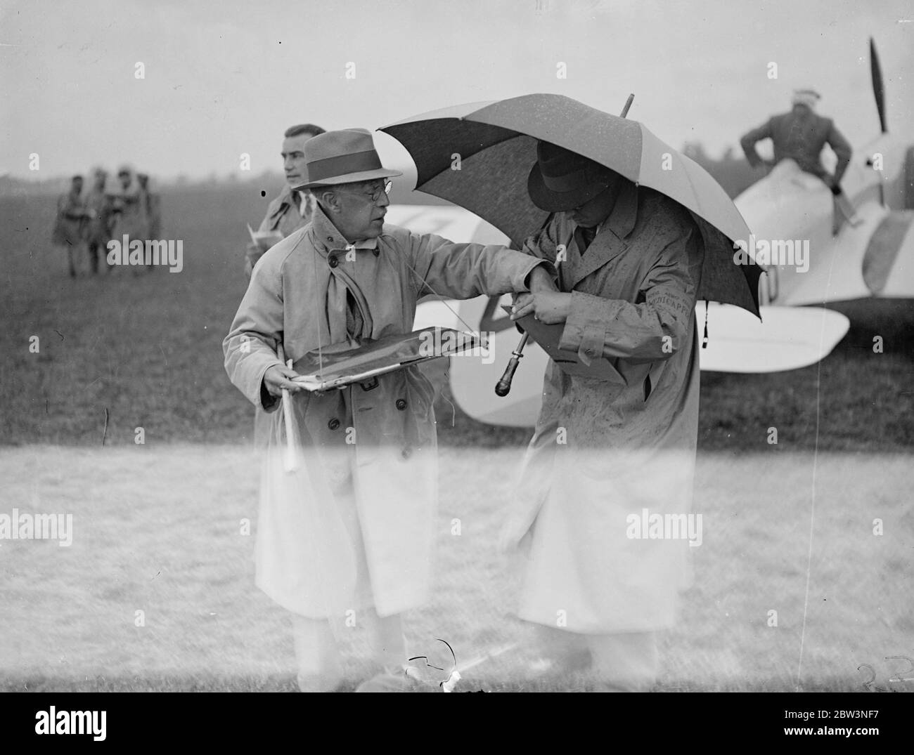 Il Sig. A. G. Reynolds , Starter ufficiale e Capitano Danney alla King' s Cup Air Race . I concorrenti della King' s Cup sono tornati all'Aerodromo di Hatfield dopo aver completato il primo circuito di 612 miglia . Dopo il rifornimento , gli aerei decolsero sul secondo circuito della stessa distanza . Spettacoli fotografici : il Sig. A. G. Reynolds , Starter ufficiale e Capitano Danney i disabili che prendono rifugio . 10 Jul 1936 Foto Stock