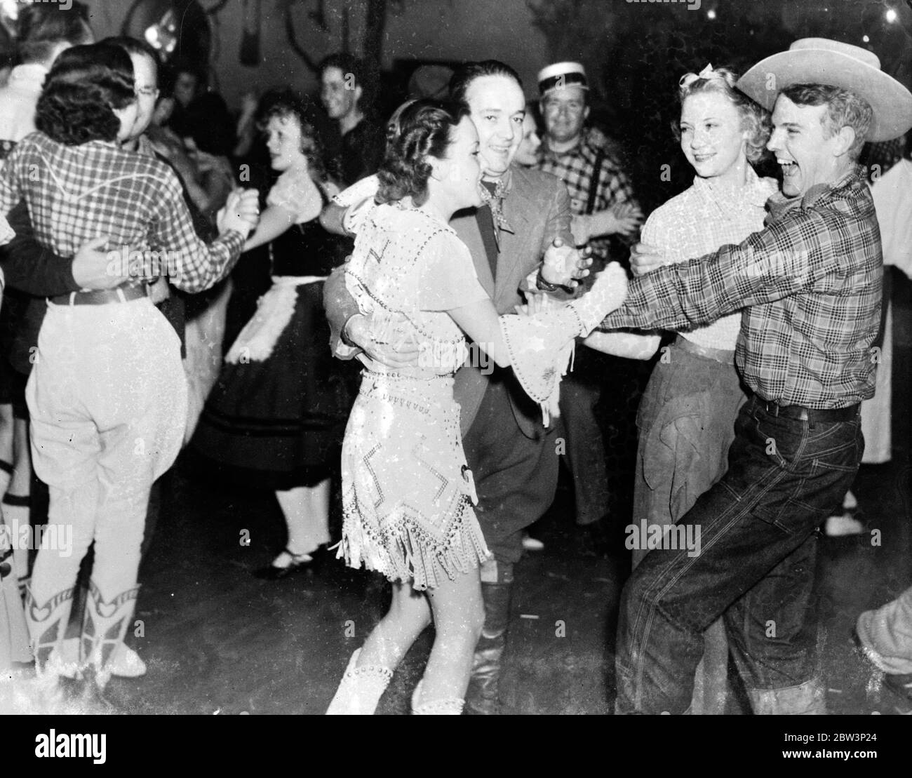 Hollywood diventa rustico . Le stelle si divertano a ballare in fienile . John Arledge , ballando con Miss Merkel ( a destra ) vede qualcosa di divertente nel reclutare Dorothy Dee ( centro ) . 20 dicembre 1935 Foto Stock